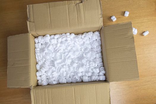 A cardboard box with packing foam top view, Delivery box for fragile product on wooden table copy space