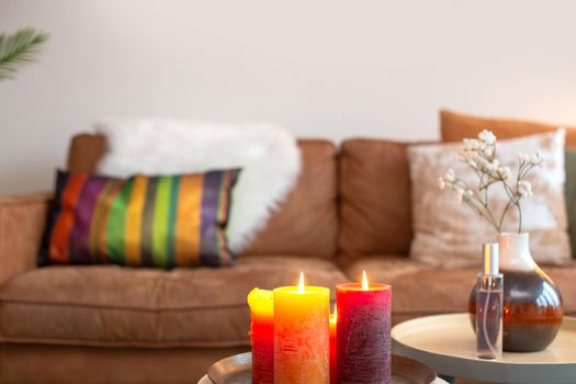 bright colorful interior living room with sofa on the background with burning candles blurred background, modern decoration style, copy space for lovely,cozy home interior concept stylish space for text