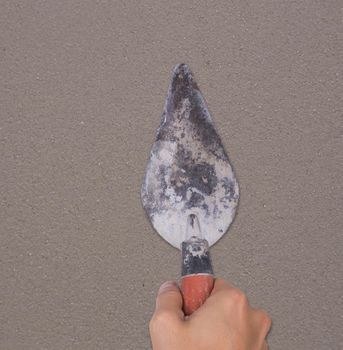 hand of builder worker use trowel plastering concrete at wall