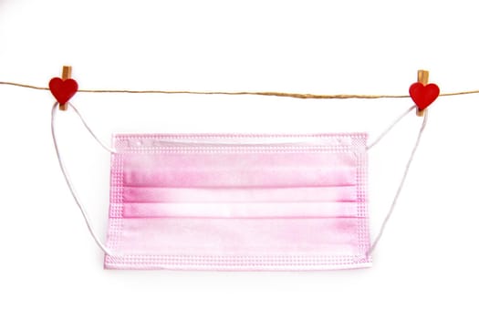 Pink protective medical mask hanging with clothes pegs in heart shape isolated on white background, Health, Covid-19 or Valentine's Day concept background love