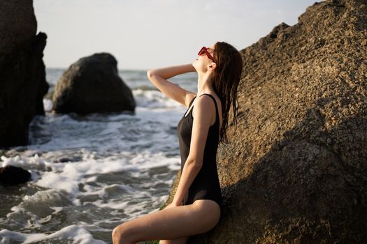 woman in black swimsuit rocks posing oceans. High quality photo