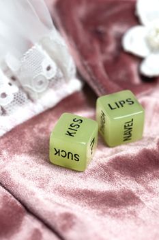Two dice for erotic sexual game with the text kiss lips and neck on pink satin fabric background, Valentines Day, Love, Sex concept playful game couples
