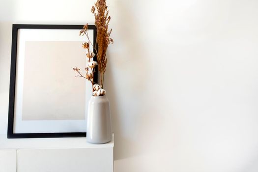 Empty wooden photo,picture frame mock-up with white vase and stylish plant near white wall on table, Copy space modern decoration interior space for text