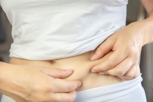 Young female wearing white underwear checking and squeeze her belly fat condition stomach closeup