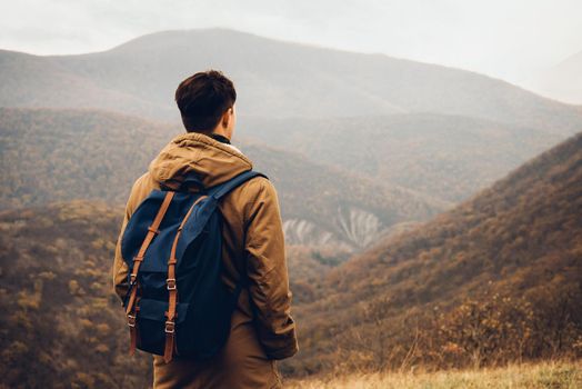 Traveler man with backpack standing on hill and enjoying by scenic of mountains, rear view