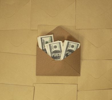 Craft paper envelope with one hundred dollar bills on brown plain background top view, copy space, business and financial concept background space for text