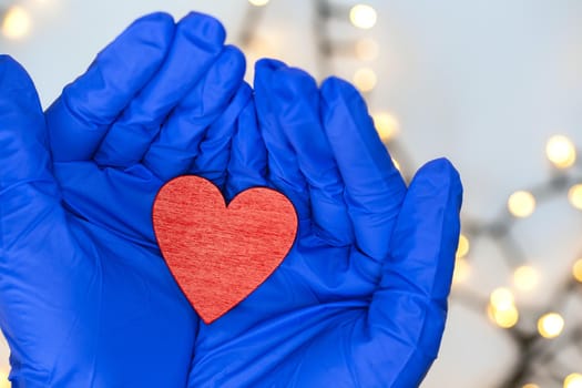 Two protective blue medical gloves holding a red heart for hope Covid-19 and health concept. Coronavirus,virus and medical background top view close up