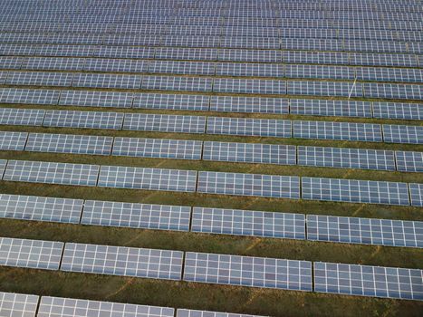 Aerial top view of a solar panels power plant. Photovoltaic solar panels at sunrise and sunset in countryside from above. Modern technology, climate care, earth saving, renewable energy concept