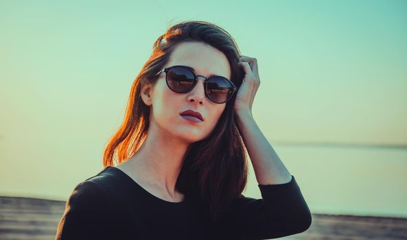 Portrait of beautiful fashionable woman with hairstyle in sunglasses on beach