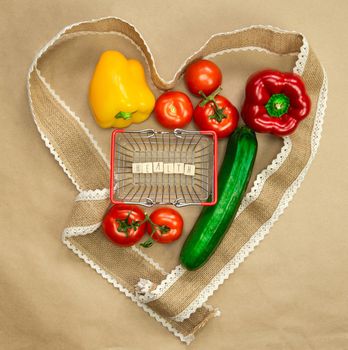 Fresh organic vegetables with the word Health in shopping basket surrounded with ribbon heart on brown craft paper top view, Health,vegan,vegetarion concept background