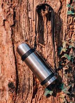 Thermos hanging on a tree. Hiking and travel theme