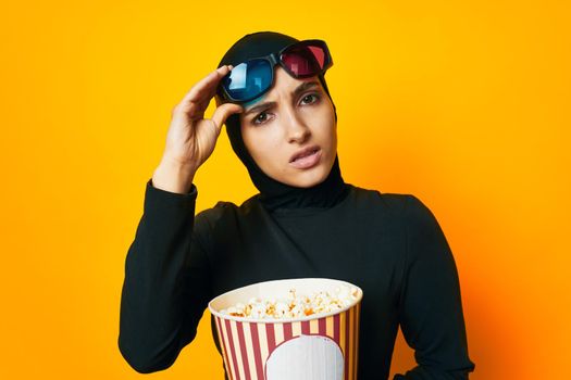 cheerful woman in black hijab popcorn 3D glasses cinema ethnicity model. High quality photo