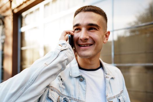 Young casual man walking on the city street and talking on the phone, close up portrait