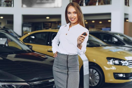 Young happy woman buyer/seller near the car with keys in hand close up