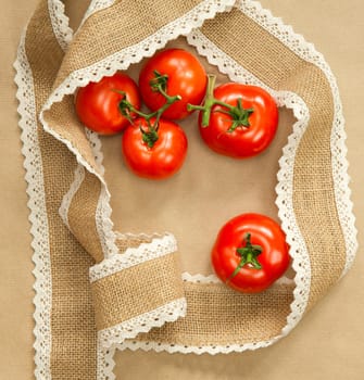 Red Tomatoes on brown craft paper background with natural colored burlap ribbon top view, copy space, Vegan, vegetarian,healthy food,vegetables concept space for text