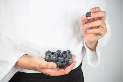 Hand holding blueberry, isolated on white background.