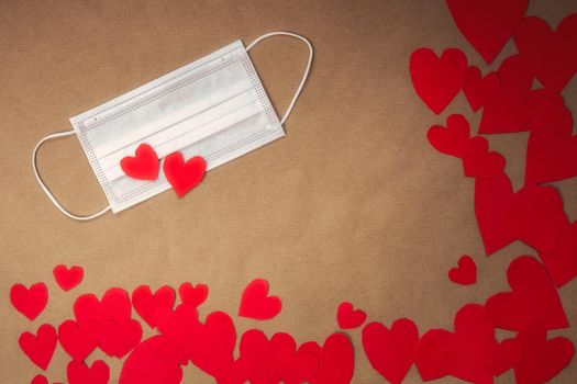 Various red hearts and white face protection medical mask, Valentines Day and Coronavirus concept top view on brown paper background. copy space romantic