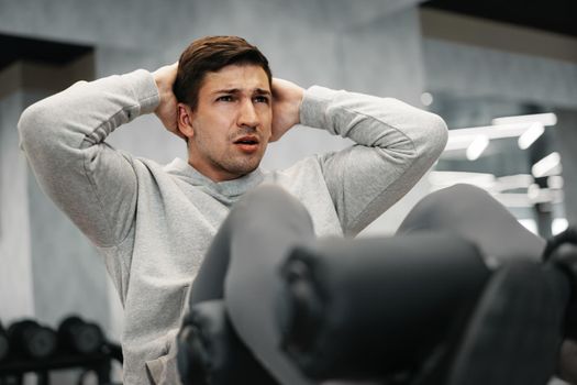 Young athlete doing abs exercises workout in modern gym, close up