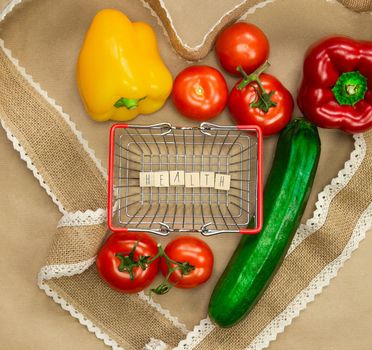 Fresh organic vegetables with the word Health in shopping basket surrounded with ribbon heart on brown craft paper top view, Health,vegan,vegetarion concept background