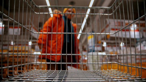 A man buying stuff - grocery trolley in the supermarket. mid shot