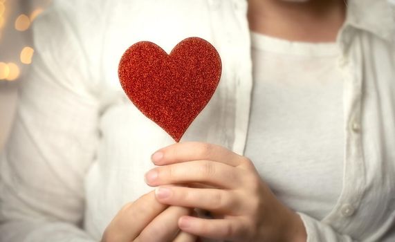 Female hands holding sparkling red heart near body, taking care, Health, Valentine's Day concept romantic design love background
