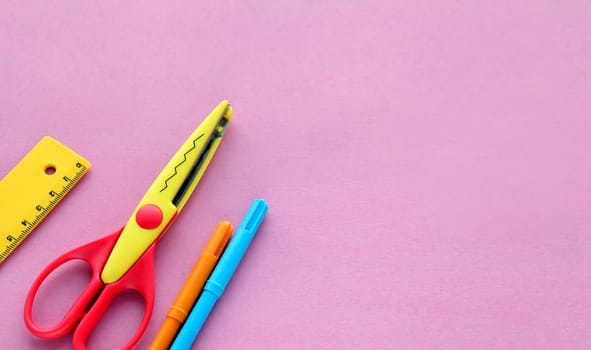 scissors, ruler and crayons on a pink background. Creative, fashionable, minimalistic, school or office workspace with supplies on cyan background. Flat lay.