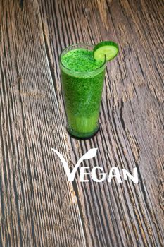 Healthy fresh green shake or smoothie with green vegetables spinach, avocado, apple on wooden background texture with the text Vegan top view, copy space freshness