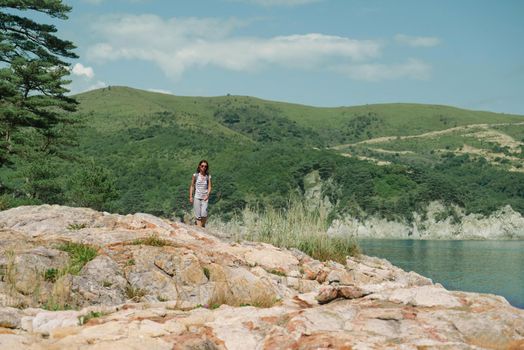 Traveler young woman walking in summer mountains near the sea