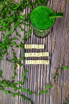 boost your immune system - inspirational text on a wooden background texture with a glass of fresh green, vegetable juice, healthy lifestyle and wellbeing concept modern design