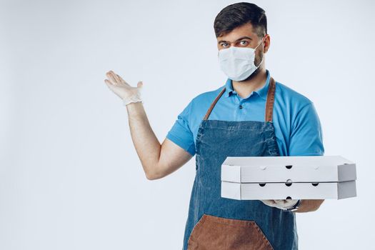 Pizza delivery man in medical gloves and mask against grey background. Safe service while coronavirus covid-19 outbreak