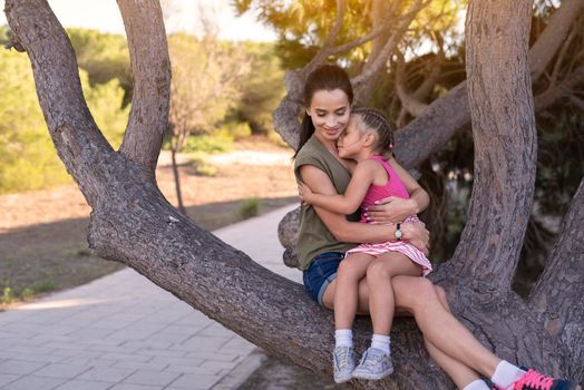 Beautiful mother and her little daughter outdoors. Beauty Mum and her Child playing in Park together at sunset. Outdoor Portrait of happy family. Mother's Day.