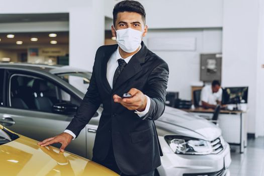 Man car dealer wearing protective medical mask on his working place, coronavirus prevention concept