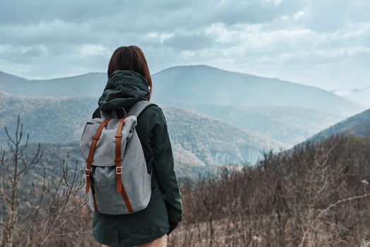 Hiker woman with backpack in mountains at autumn season