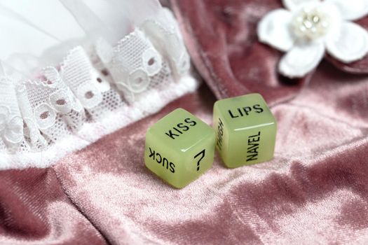Two dice for erotic sexual game with the text kiss lips and neck on pink satin fabric background, Valentines Day, Love, Sex concept playful game couples