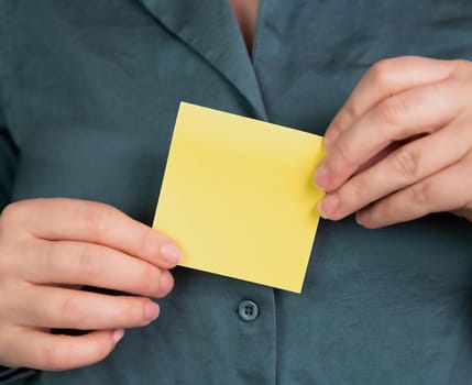 Business woman holding a blank yellow memo notepaper, sticky note for copy space, space for text, business,communication,education,design concept close-up