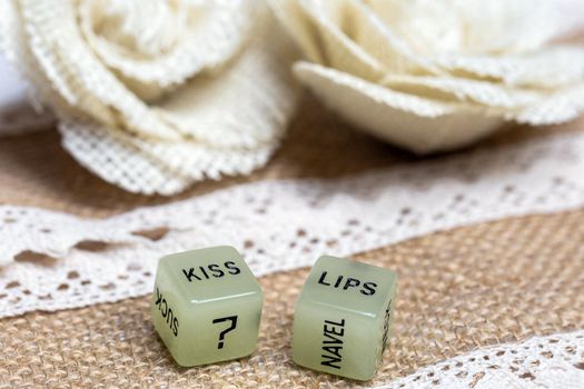 Two erotic dice for sexual game with cotton lace background texture, with the text Kiss lips for Valentines Day,sex,sensual,romantic, love concept close up