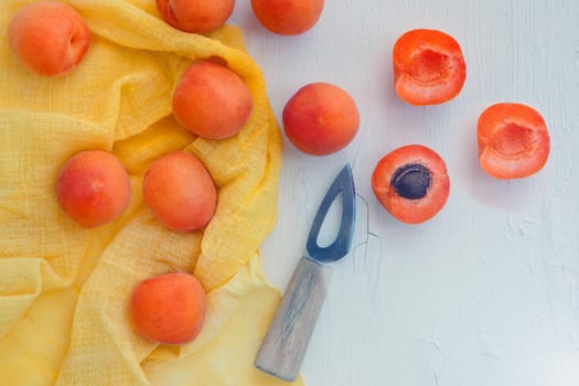 Delicious apricots with small knife on table close-up. Horizontal view from above with yellow napkin. space for text