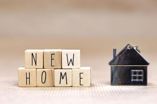 New Home text written with wooden cubes background with symbol of cozy little house with blurred background design, purchase real estate,mortgage loan, property owner concept background close up