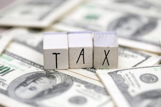 Tax text with hundred dollar bills background, business, financial and tax time concept close up