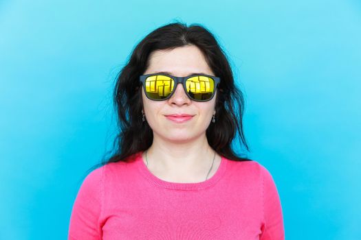 Fashion happy pretty smiling woman wearing a sunglasses over colorful blue background.