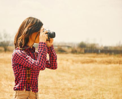 Young woman takes photographs with vintage photo camera in autumn outdoor