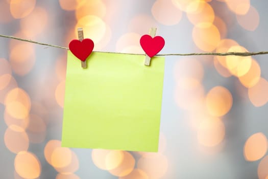 Blank Yellow sticky note hanging with red hearts with bokeh background, romantic Valentines day concept background copy space love