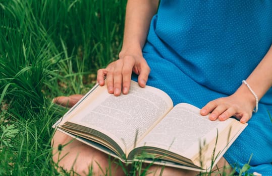Unrecognizable woman reading a book in summer park outdoor