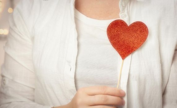Female hands holding sparkling red heart near body, taking care, Health, Valentine's Day concept romantic design love background