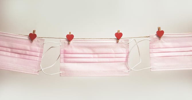 Pink protective medical mask hanging with clothes pegs in heart shape isolated on white background, Health, Covid-19 or Valentine's Day concept background love