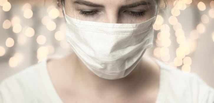 Young female wearing protection face mask against coronavirus looking down bokeh background. medical staff preventive gear. Covid-19 and Health concept background bokeh background