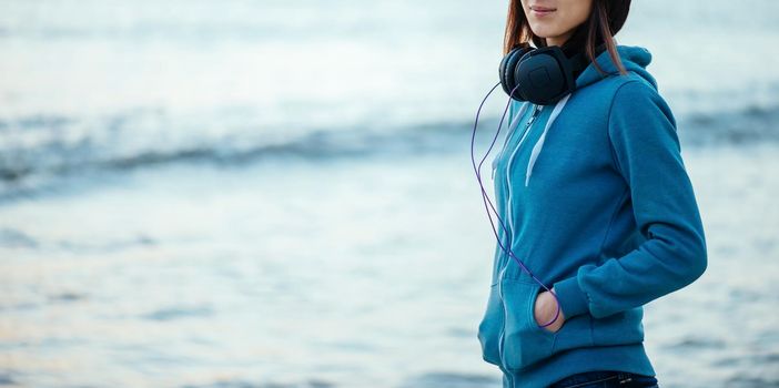 Girl with big headphones walking on beach near the sea