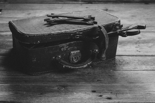 Working tools in vintage case on a wooden table. With film grain and low contrast effect. Black-white photo.