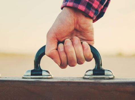 Close-up image of female hand with suitcase handle