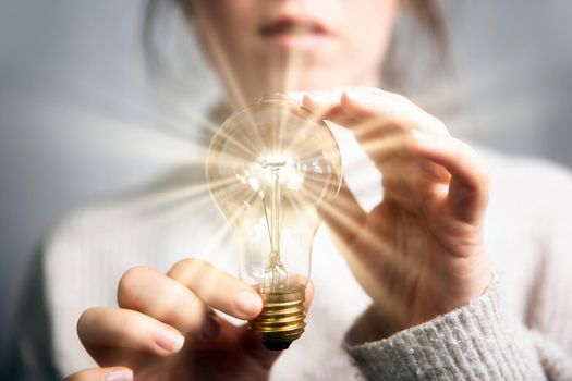 Female hand holding a shining light bulb, Great idea, innovation and inspiration, business concept background modern retro design